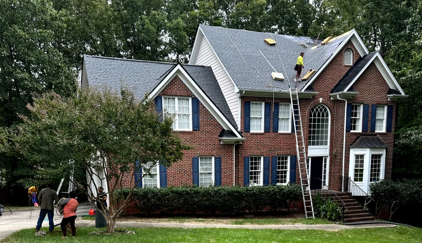 Citadel roofers working on a brick colonial home with ladders set at the front