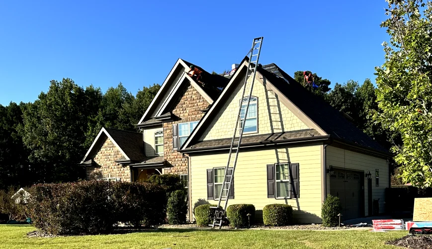 Citadel crew with ladders replacing the roof on a two-story yellow home